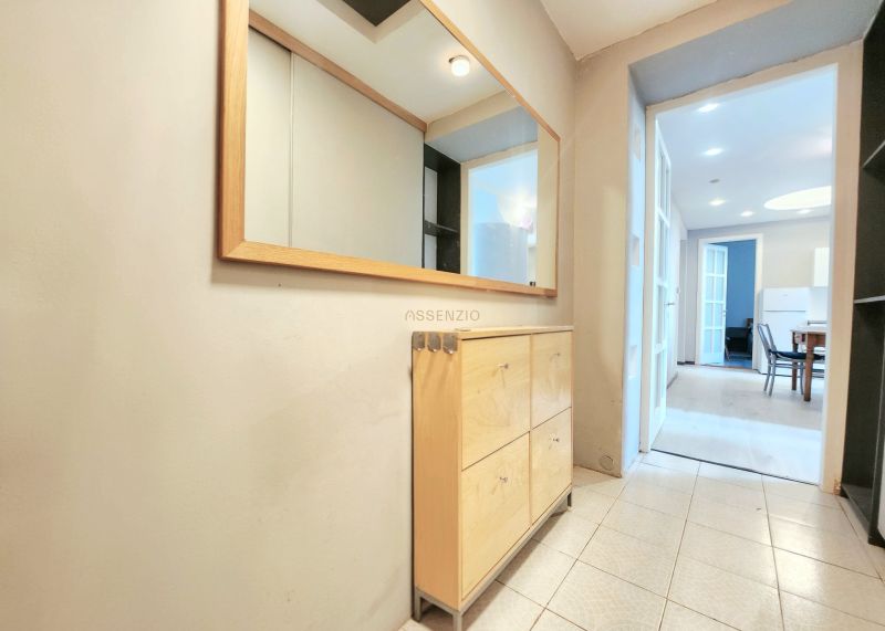 A hallway in a 2-room apartment with wooden furniture, tiles, and a large mirror.