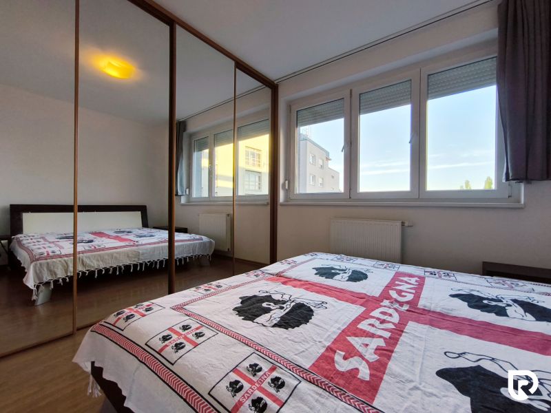 Bedroom with a large mirrored wardrobe in a 2-room apartment, floor with wood decor.