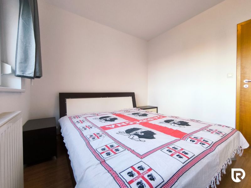 A bedroom in a 2-room apartment with a bed and a wooden decor floor.