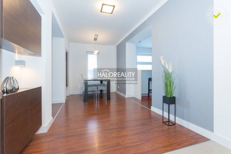 A bright dining room with wood-patterned flooring in a family house, light walls, modern lighting fixtures.