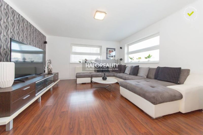 A living room in a family house with a wooden decor floor and a large corner sofa.