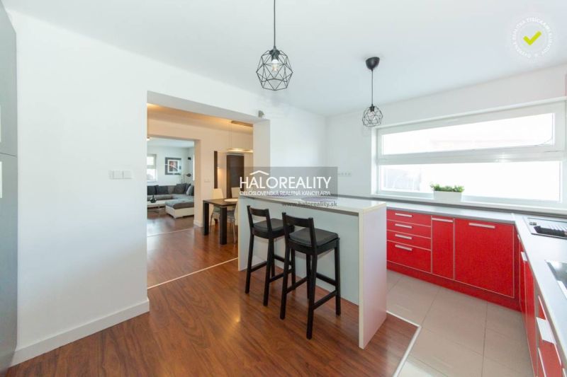 A kitchen in a family house with red kitchen cabinets and a wooden decor floor.