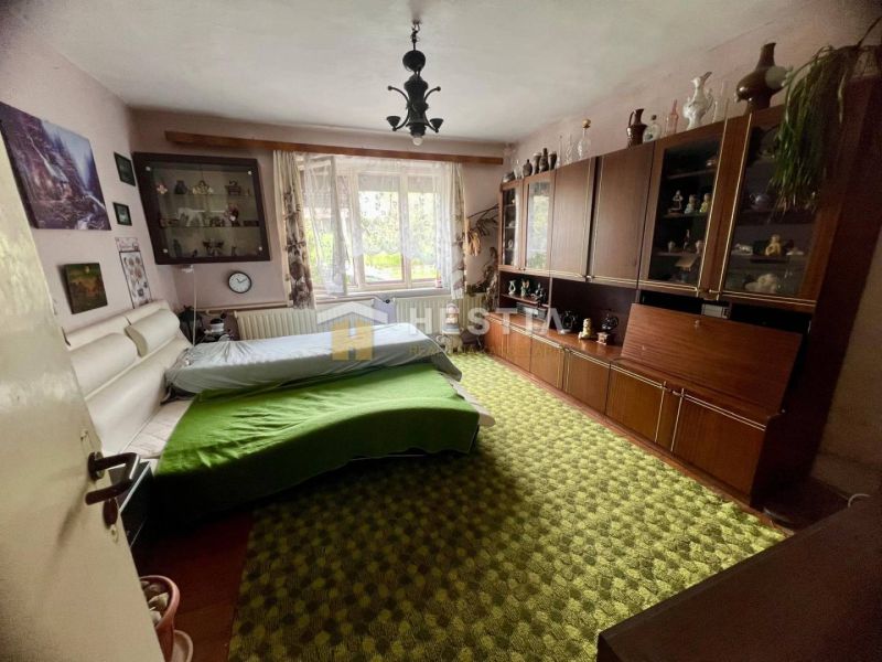 Bedroom in a family house with carpeted floor, wardrobe set, and large window.
