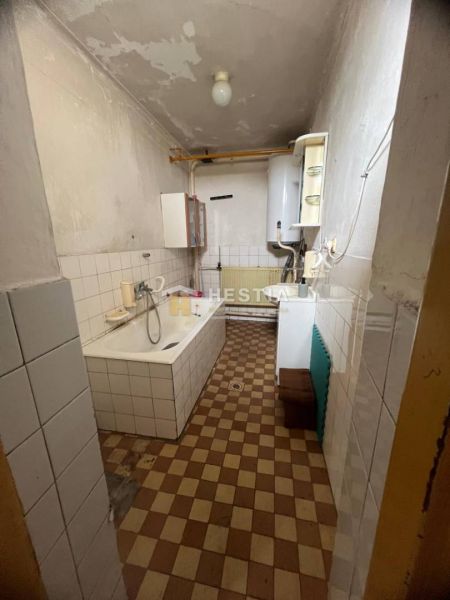 A bathroom with a bathtub in a family house, tiled with a radiator and a gas boiler.
