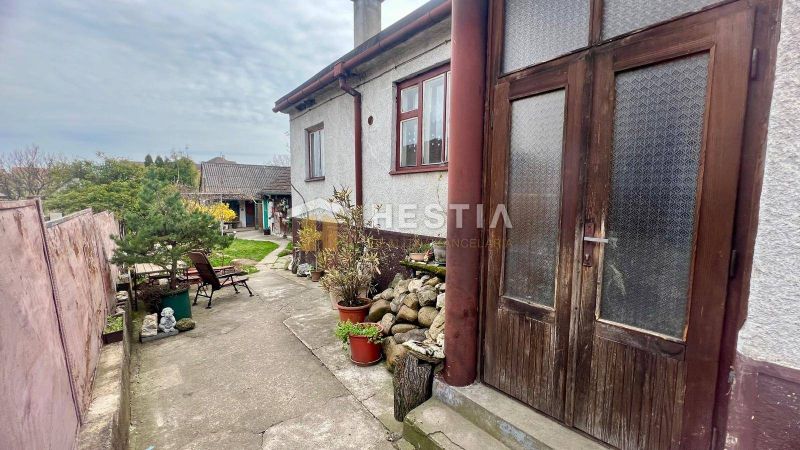 A family house in Cerová with courtyards and greenery, bordered by wooden and stone elements.