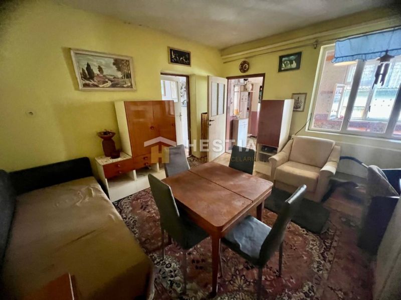 Living room of a family house with a carpet, wooden furniture, and wall paintings.
