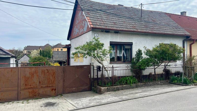 A family house in Cerová with a gate and a small garden, surrounded by greenery.