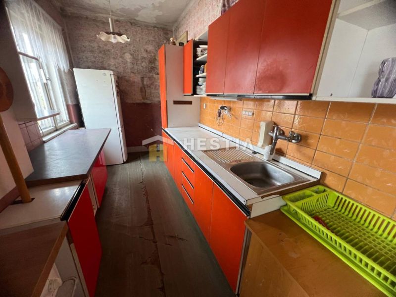 A kitchen in a family house with orange cabinets and a wood-patterned floor.