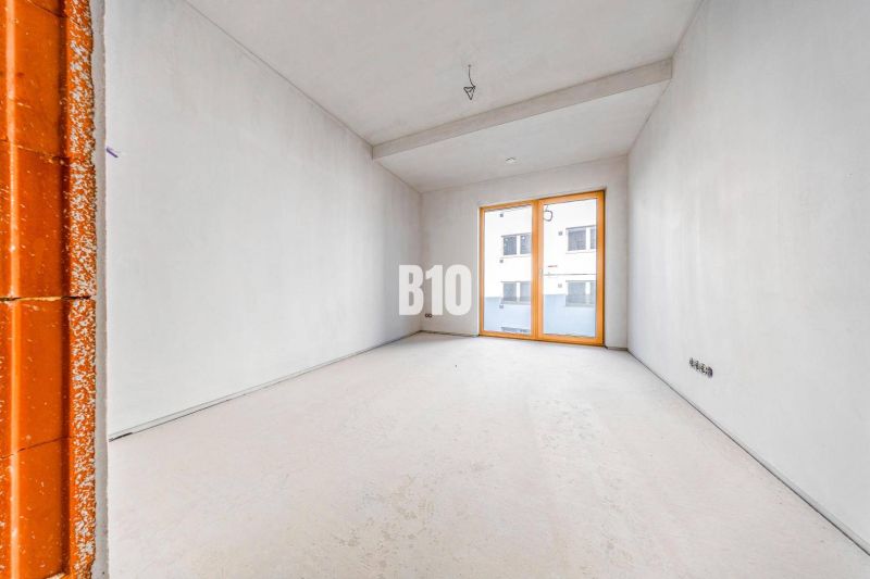 Empty room with a concrete floor and large windows in a 3-room apartment.