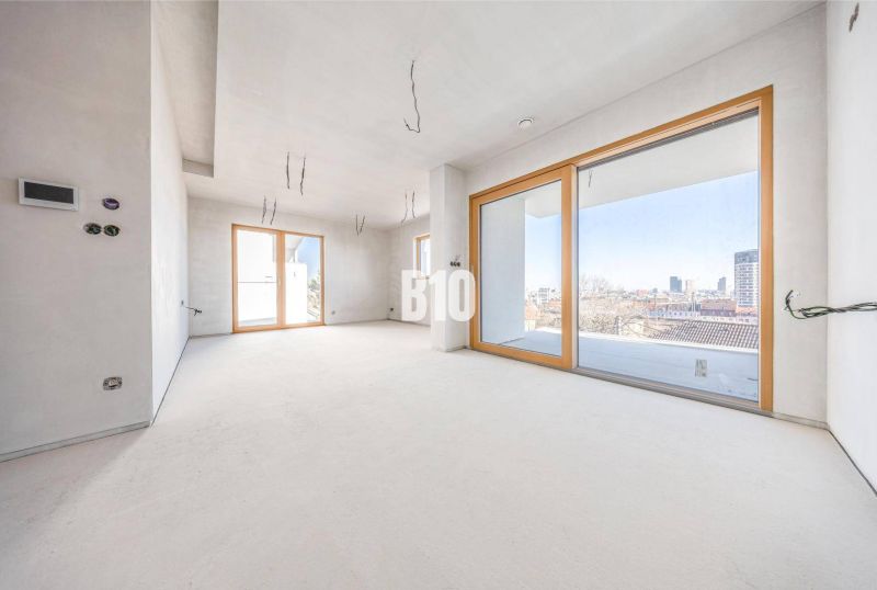 Spacious bright interior in a 3-room apartment with large windows and neutral flooring.