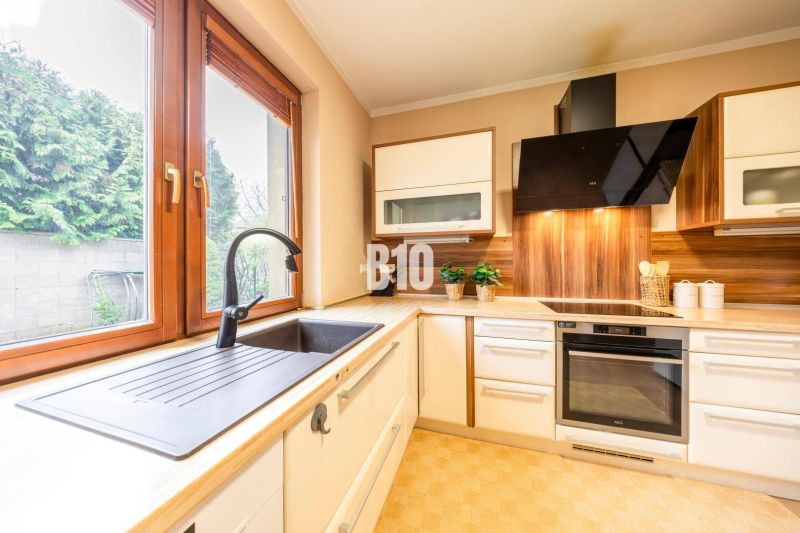 A kitchen in a family house with a wooden decor floor and wooden windows.
