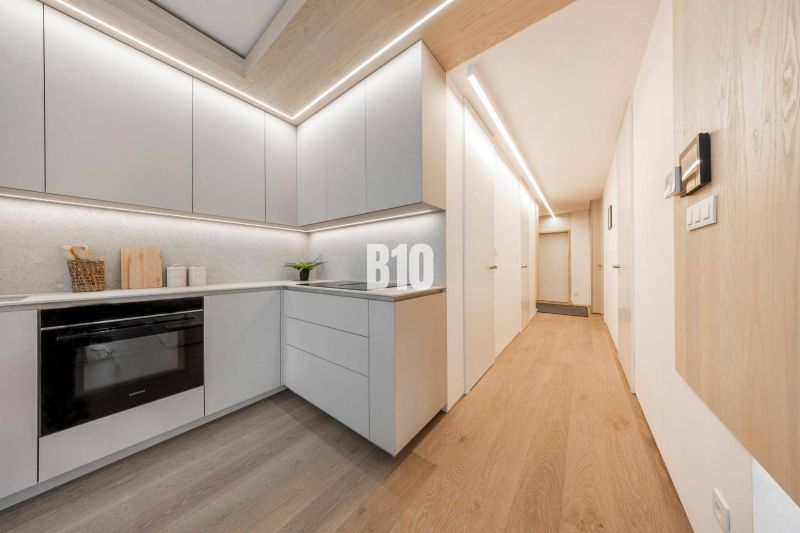 A kitchen in a 3-room apartment with a wooden decor floor and light furniture.