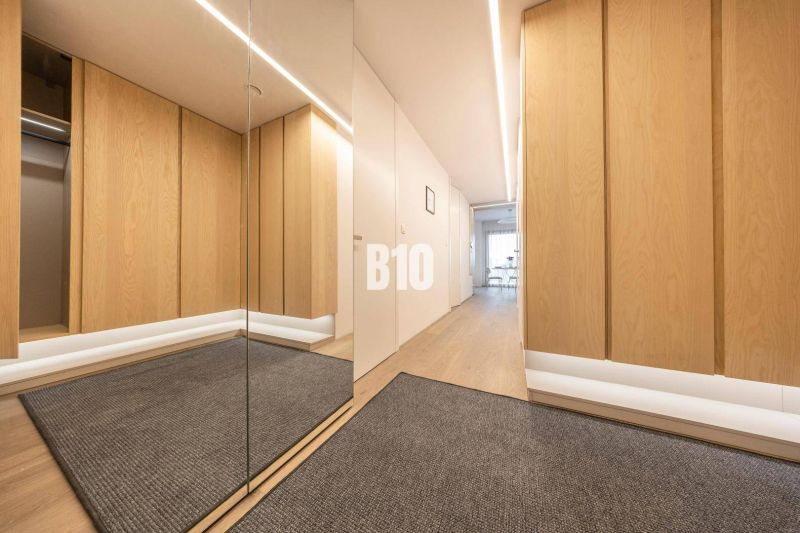 A hallway in a 3-room apartment with a wooden decor floor and a mirror.
