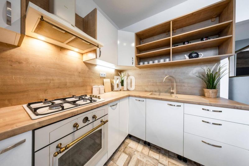Kitchen in a 2-room apartment, light cabinets, open shelves, wooden decor flooring.