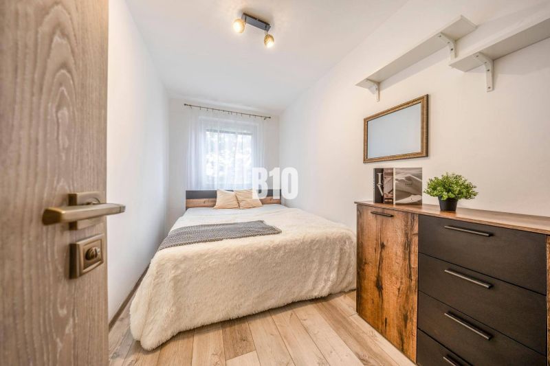 Bedroom with a bed, dresser, and wooden decor flooring in a two-room apartment.