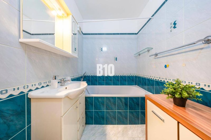 A bathroom with a bathtub and a sink in a 2-room apartment with blue and white tiles.