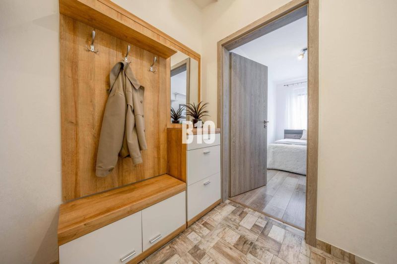 Entrance hallway with a coat rack and a view into the bedroom in a 2-room apartment.