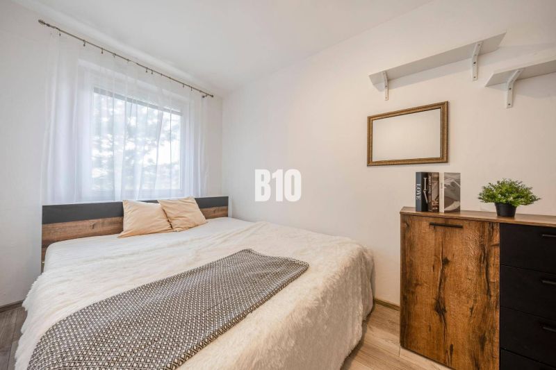 Bedroom in a two-room apartment with a bed, shelves, and a floor with a wood decor.
