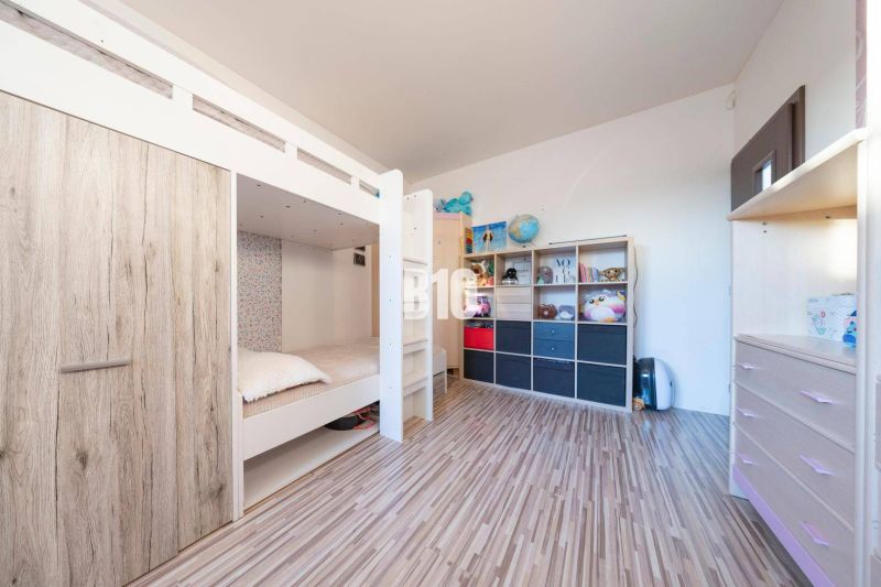 Children's room with a bunk bed, storage space, and a floor with a wooden decor.