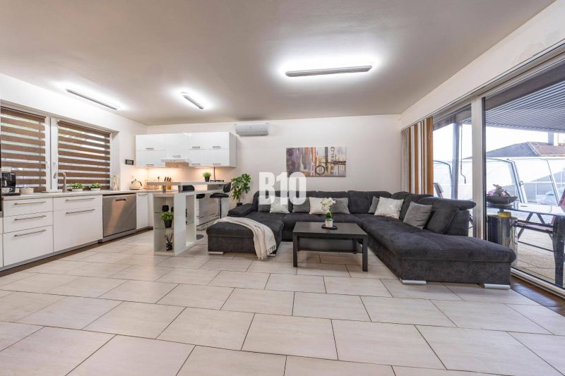 A bright living room in a family house with a kitchen and a large sofa.