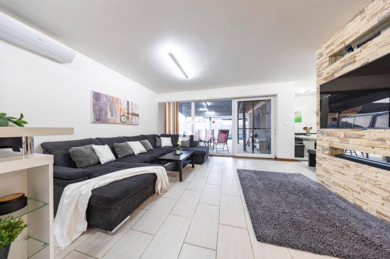 Living room of a family house with a sofa, fireplace, and sliding doors to the terrace.