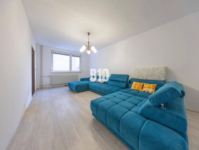 Living room in a 4-room apartment with a turquoise sofa and a wooden decor floor.