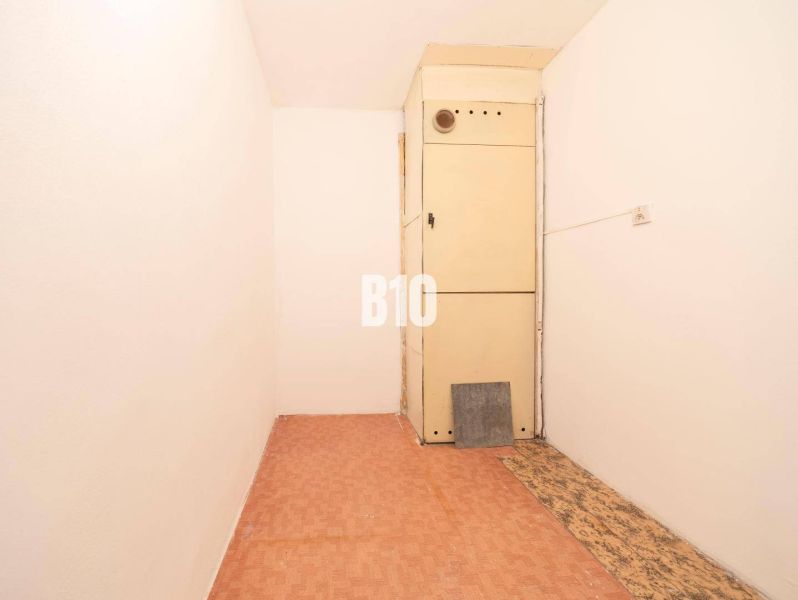 A narrow room in a 4-room apartment with a wooden decor floor and a cabinet.
