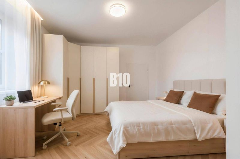 Bedroom in a 4-room apartment with wood-patterned flooring, a desk, and a built-in wardrobe.
