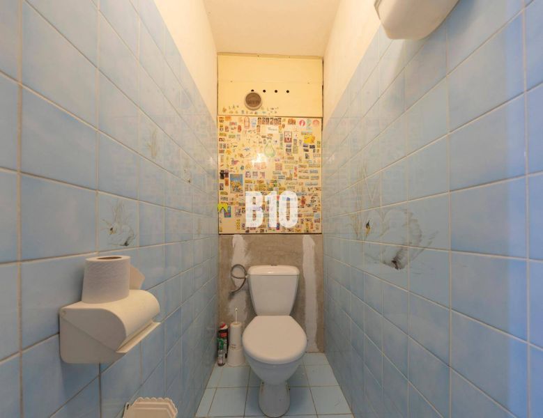 A bathroom in a 4-room apartment with blue tiles and a toilet.