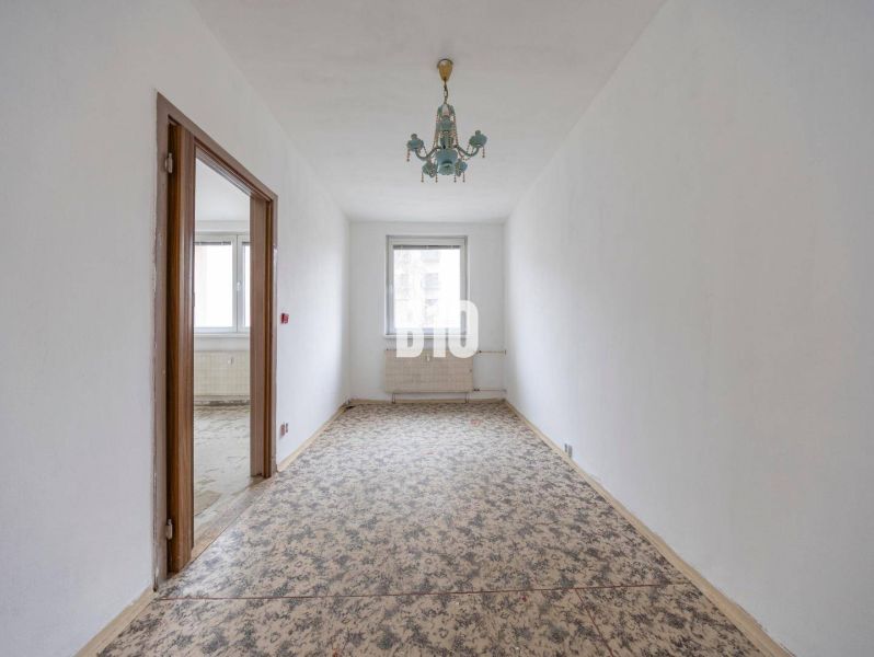 A narrow room in a 4-room apartment with a carpet and a vintage chandelier.