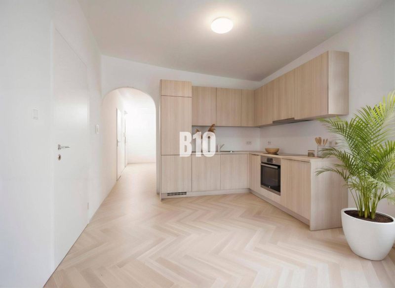 A kitchen in a 4-room apartment with a wooden decor floor and light furniture.