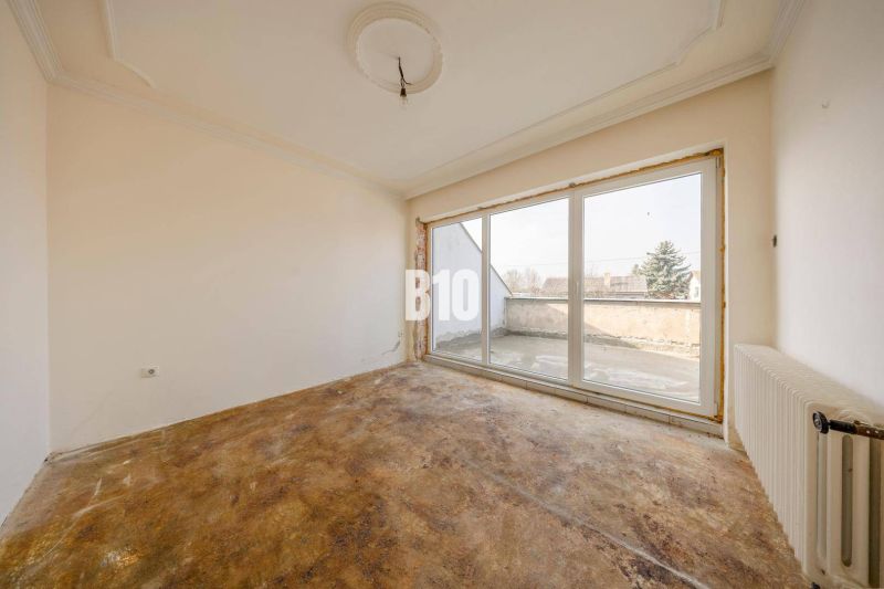 Empty room with large windows and flooring in a family house.