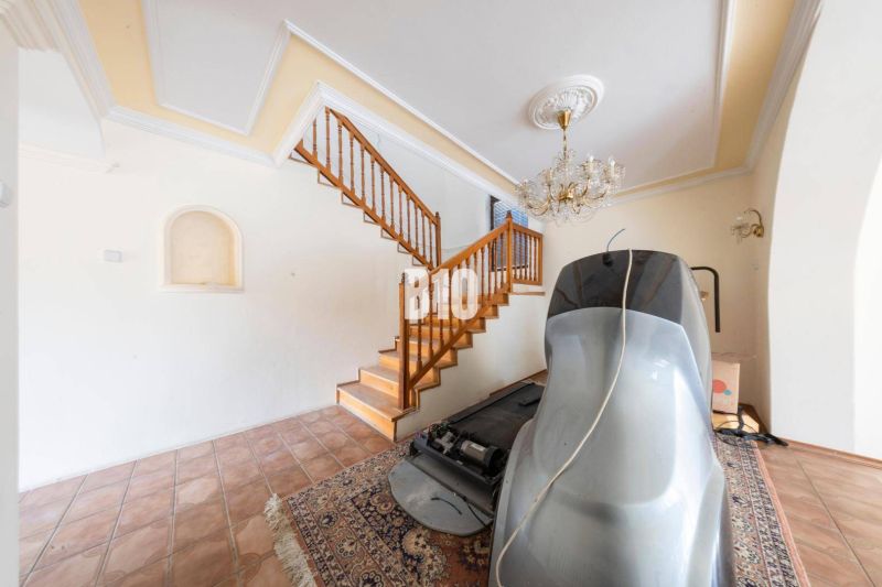 Interior of a family house with a staircase, chandelier, flooring, and sports equipment.
