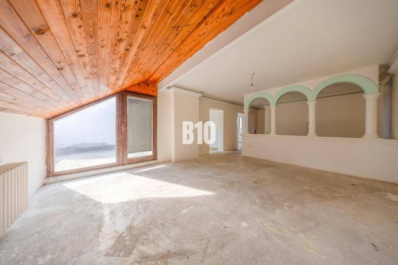 Spacious interior of a family house with a large window and a wooden ceiling.
