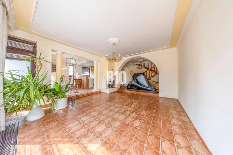 Interior of a family house with ceramic flooring, a staircase, and houseplants.