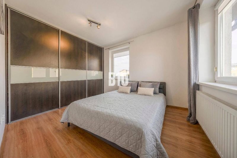 Bedroom in a 2-room apartment with a wood-patterned floor and a large built-in wardrobe.