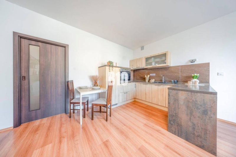Kitchen corner in a 2-room apartment with a wooden decor floor and a dining table.