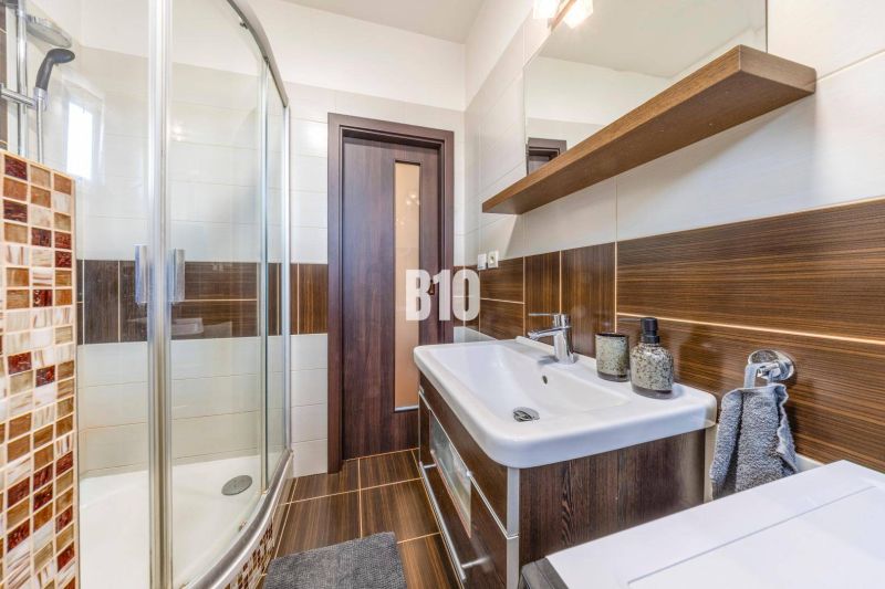 The bathroom in the two-room apartment has a shower and a cabinet with a sink.