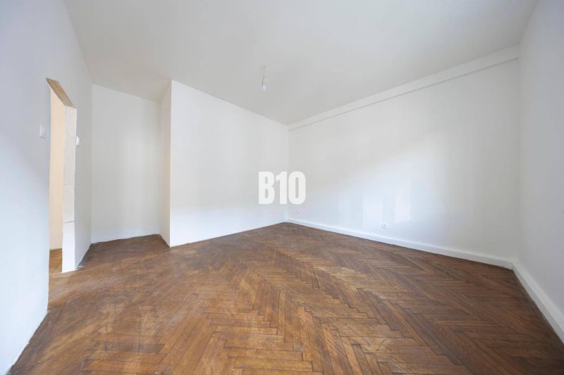 A spacious room with white walls and a wood-decorated floor in a 3-room apartment.