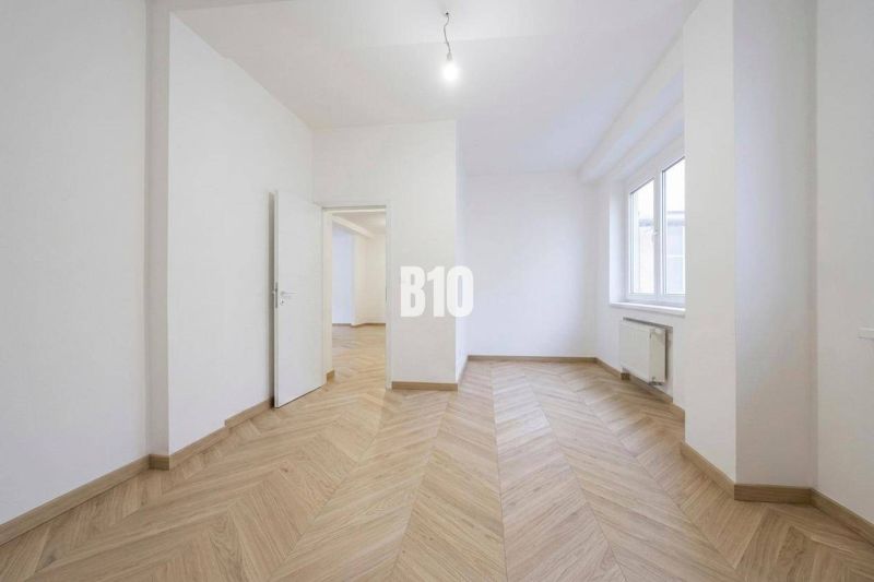 A room with white walls and a wooden decor floor in a 3-room apartment.