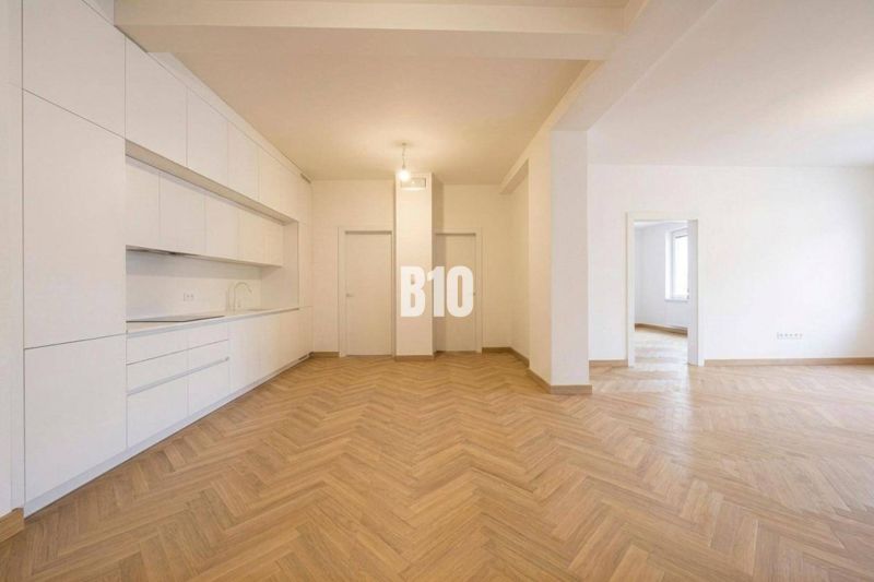 Interior of a 3-room apartment with a white kitchen and a floor with a wood decor.