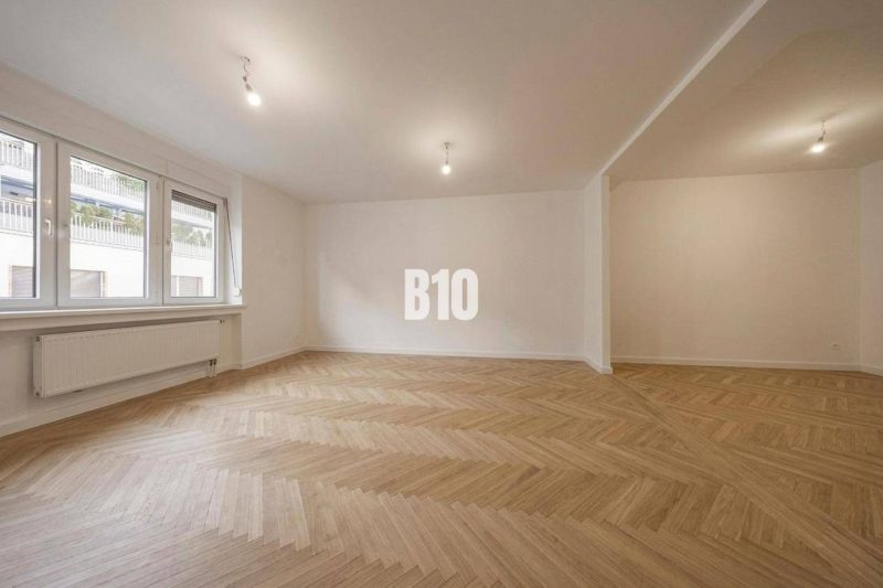 A spacious room with a wooden decor floor in a 3-room apartment.