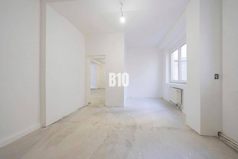 An empty 3-room apartment interior with white walls and a large window.