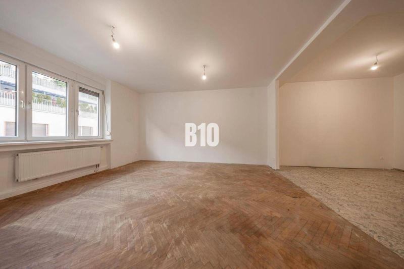 Living room in a three-room apartment with a wooden decor floor and large windows.