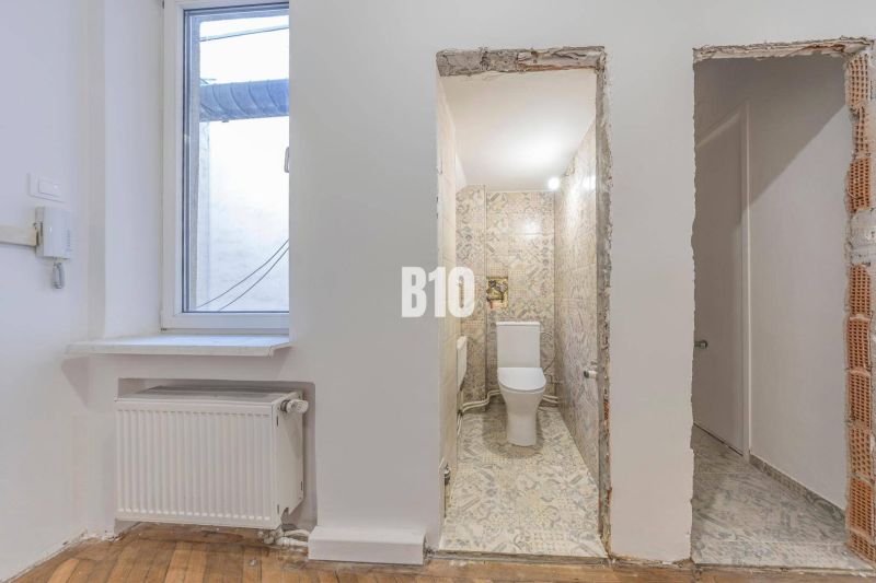 Bathroom with ceramic tiles and a window, next to it a floor with a wood decor.