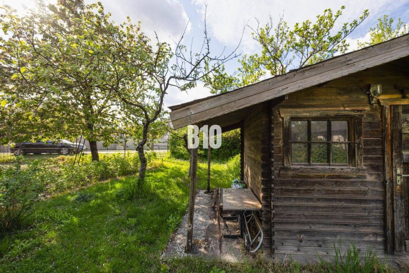 A garden with a wooden cottage surrounded by trees on a plot in Dunajská Lužná for living.