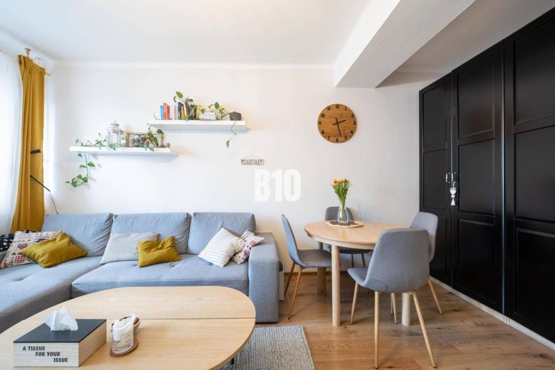 Living room with a gray sofa, round table, and wood-patterned flooring in a two-room apartment.