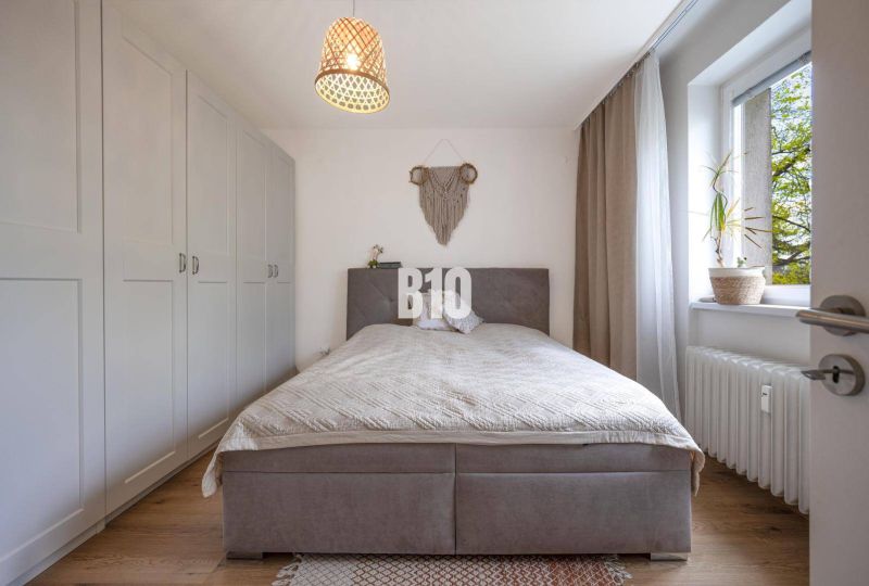A bedroom with a comfortable bed, built-in wardrobes, and a window in a 2-room apartment.