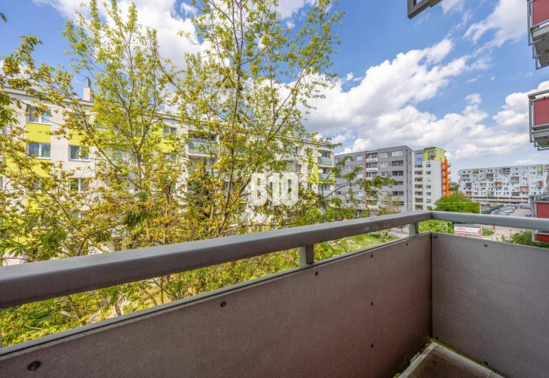 A narrow loggia in a 2-room apartment with a view of apartment buildings surrounded by greenery on Vietnamska Street.