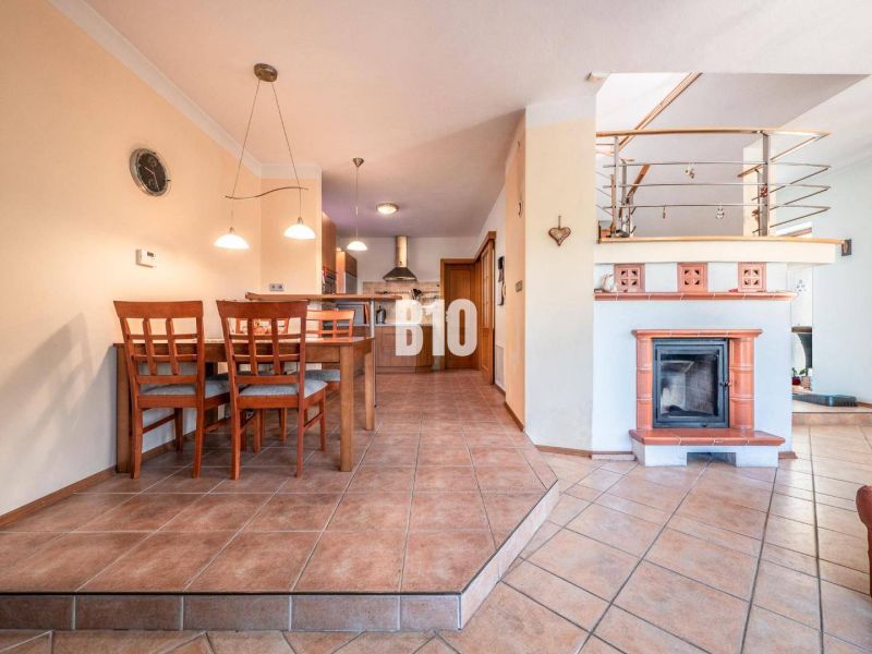 Dining room with a fireplace and kitchen in a family house with ceramic tiles.